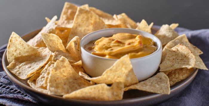 plate of tortilla chips with queso dip in bowl