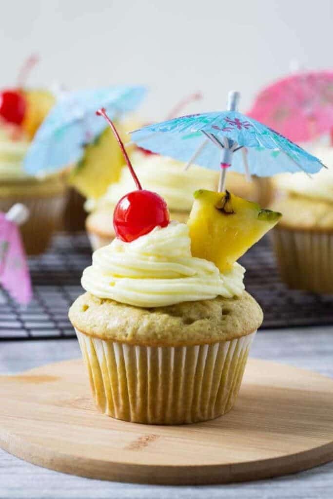 pina colada cupcake with umbrella, maraschino cherry, and pineapple wedge