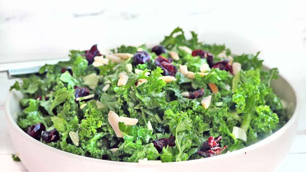 a bowl of kale salad with nuts over the top