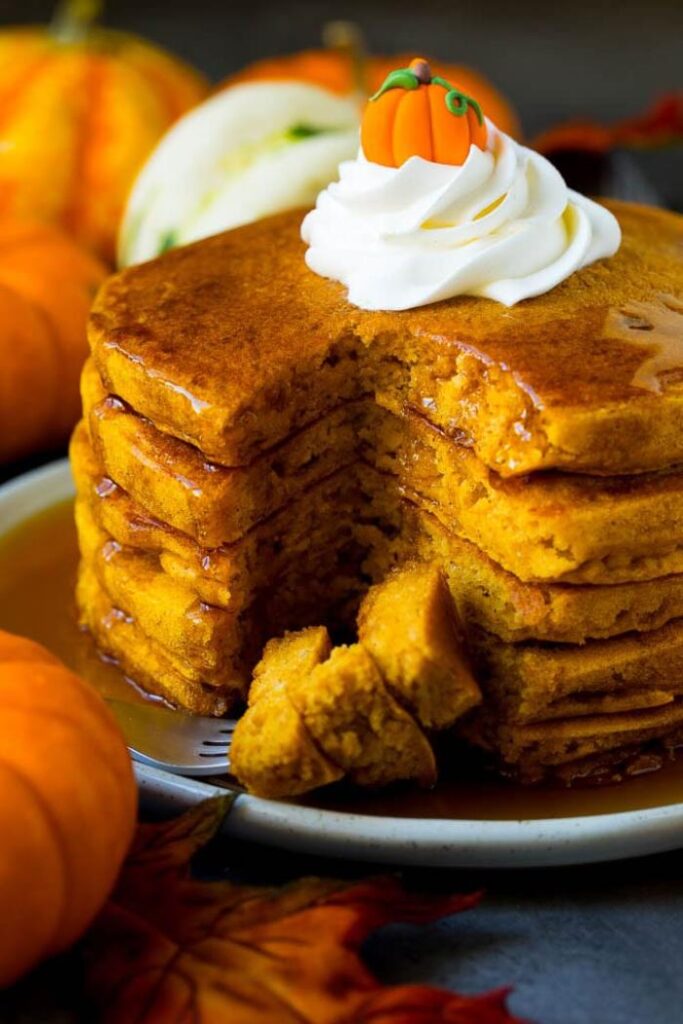 stack of pumpkin pancakes with whipped cream