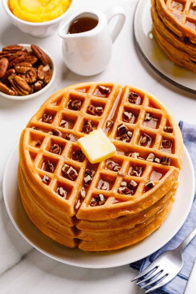 stack of pumpkin waffles with butter and syrup