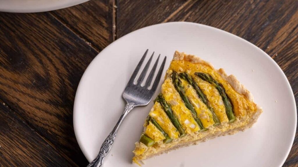 a slice of quiche with asparagus stalks on the top