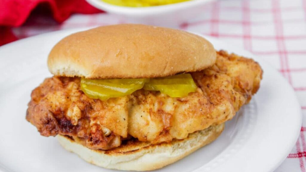 a chicken sandwich with pickles on a plate