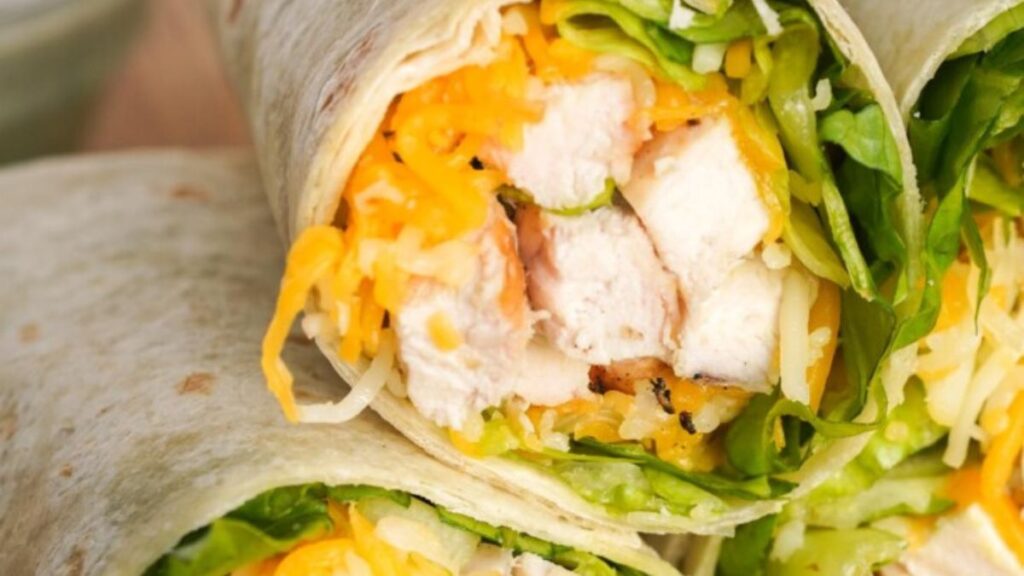 a chicken wrap cut in half, with lettuce, chicken and ranch