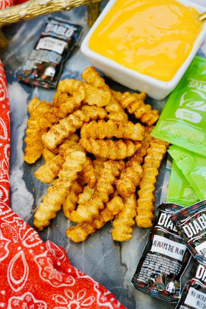 nacho fries displayed with sauce packets and bowl of cheese sauce