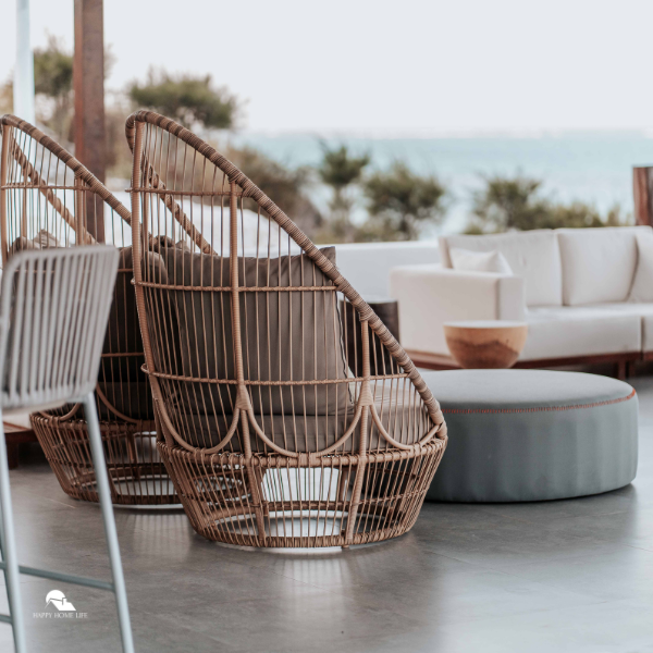 Two modern wicker chairs with cushions arranged in a stylish outdoor setting overlooking greenery and the sea, creating a serene and family-friendly space.